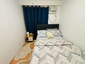 a bedroom with a bed with a blue curtain at Thea's Place Arezzo Place in Davao City