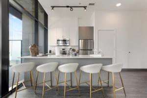 a kitchen with a counter with four white stools at CoWorking Gym Pool Golfsim Steps from FultonMarket by Cloud9-160 in Chicago