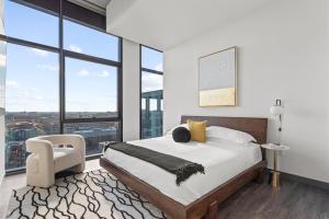 a bedroom with a bed and a chair and windows at CoWorking Gym Pool Golfsim Steps from FultonMarket by Cloud9-160 in Chicago