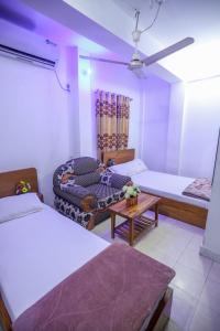 a room with two beds and a couch and a table at Hotel City International Green Road in Dhaka