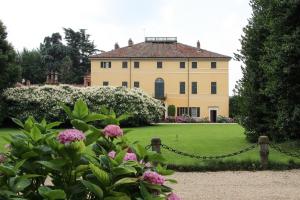 una casa grande con un patio con flores rosas en Agriturismo Il Torrione en Pinerolo