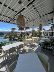a patio with white tables and chairs and a view at La Madriguera in Guatapé