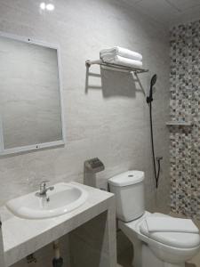 uma casa de banho com um lavatório, um WC e um espelho. em Grand Mulia Hotel Kisaran em Kisaran