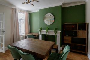 a dining room with a wooden table and green walls at The Green House 3 Bed House - Contractors, Families, Free Parking, close to racecourse and city centre in Doncaster
