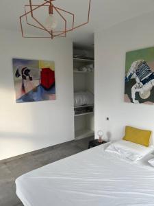 1 dormitorio con cama blanca y pinturas en la pared en Villa de 6 chambres avec piscine privee jardin clos et wifi a Saint Peray, en Saint-Péray