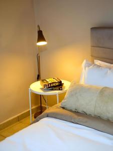 una cama con una mesa con un libro y una lámpara en Nafplio Cottage-Grandma's Yard, en Asíni