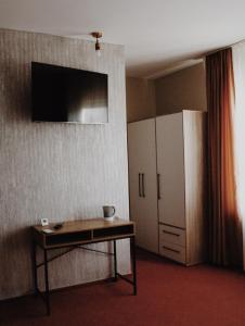 a room with a table and a cabinet and a television at Popasul Graniceresc in Năsăud