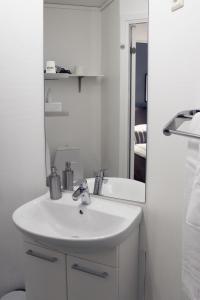 a white bathroom with a sink and a mirror at Hotell Miskarp in Mjölby