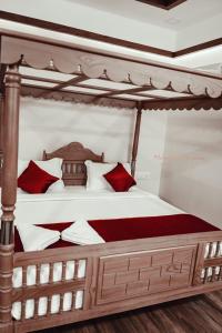 um quarto com uma cama de dossel com almofadas vermelhas e brancas em ATHIRAPPILY SREENILAYAM HERITAGE RESORt em Athirappilly
