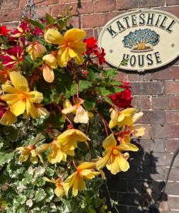 a sign for a house with yellow and red flowers at Kateshill House Bed & Breakfast in Bewdley