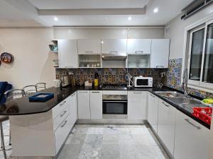 a kitchen with white cabinets and a sink at Villa Jasmin Super equipped apartment with Garden, Swimming pool, Sea in Hammamet