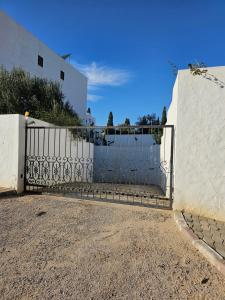 un portail en fer devant un bâtiment blanc dans l'établissement Villa Jasmin Super equipped apartment with Garden, Swimming pool, Sea, à Hammamet