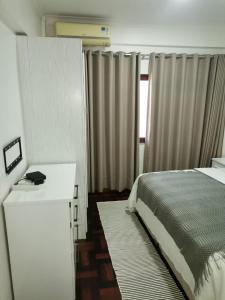 a bedroom with a bed and a desk and a window at Oásis Tropical: Flat de Luxo na Beira, Moçambique in Beira