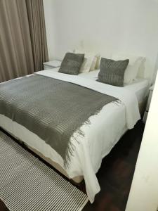 a large bed with black and white sheets and pillows at Oásis Tropical: Flat de Luxo na Beira, Moçambique in Beira