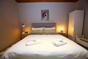 1 dormitorio con 1 cama blanca grande y 2 toallas en Nafplio Cottage-Grandma's Yard, en Asíni