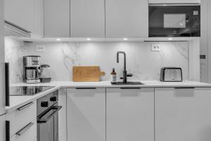 a white kitchen with white cabinets and a sink at The Nordic Hideaway in Tromsø