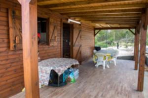 una veranda di una cabina in legno con tavolo e tavolo di Charmant chalet belle vue sur la mer 100% autonome a Le Gosier