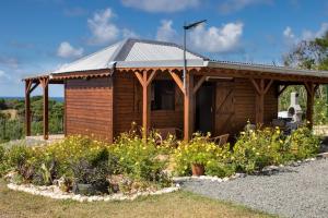a wooden cabin with a roof in a garden at Charmant chalet belle vue sur la mer 100% autonome in Le Gosier