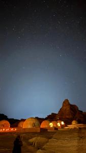 a person standing in the desert under a starry sky at RUM JOHARH lUXURY CAMP in Wadi Rum