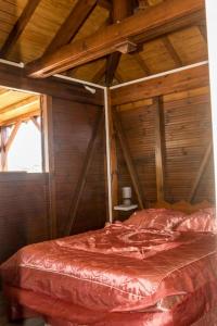 Cama grande en habitación con techo de madera en Charmant chalet belle vue sur la mer 100% autonome, en Le Gosier