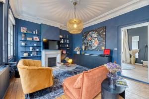 una sala de estar con paredes azules y una lámpara de araña. en Appartement balnéo centre, en Rouen