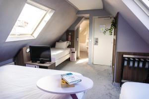 um quarto no sótão com uma cama e uma televisão em Hôtel de Charonne em Paris