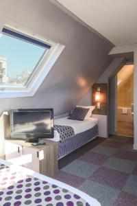 um quarto com uma cama e uma televisão de ecrã plano em Hôtel de Charonne em Paris