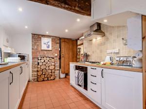 a kitchen with white cabinets and a brick wall at 2 Bed in Slimbridge 90719 in Cambridge