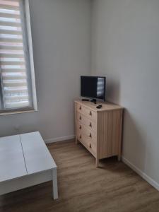 een kleine kamer met een tv op een dressoir met een tafel bij La Cigale in Soissons