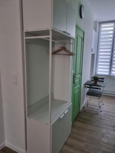 une étagère blanche dans une chambre avec une porte verte dans l'établissement La Cigale, à Soissons