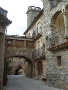 un antiguo edificio de piedra con un arco en una calle en L'Esgolfa de ca l'Ortís, en Figuerosa