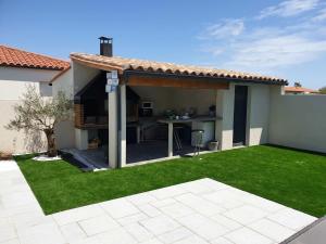 a backyard with a patio with a kitchen in it at Villa de 3 chambres avec piscine privee jardin clos et wifi a Pia in Pia