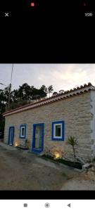 mały dom z niebieskimi drzwiami i budynkiem w obiekcie Moradias dos Castelos (Azul ) w mieście Ourém