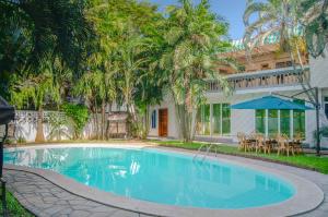 una piscina frente a una casa con palmeras en La Fattoria Resort en Mombasa