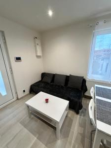 een woonkamer met een zwarte bank en een tafel bij Sublime Appt refait à neuf ! in Argenteuil