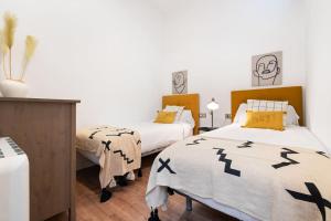 a bedroom with two beds with black and yellow pillows at Enamorats in Barcelona