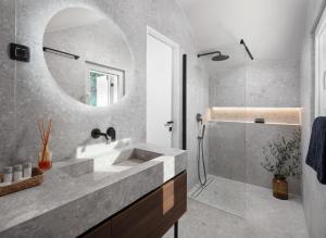 a bathroom with a sink and a shower and a mirror at Modern Seafront Villa Steps from the Beach in Rogoznica