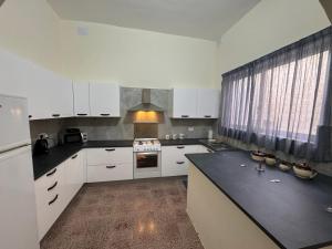 a kitchen with white cabinets and a black counter top at B&S Accommodation 1940 House of Character Żejtun, Malta in Żejtun