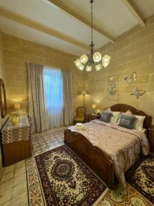 a bedroom with a large bed and a chandelier at B&S Accommodation 1940 House of Character in Żejtun