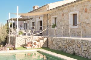 ein Haus mit einer Steinmauer und einem Pool in der Unterkunft Villa Can Caluix 268 by Mallorca Charme in Sineu