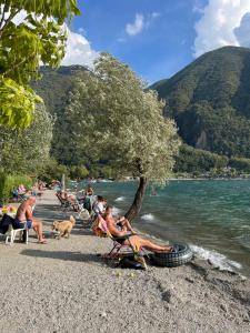 a group of people sitting on a beach with a dog at Mobile Home Italy in Porlezza