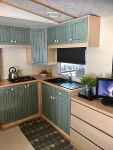 uma cozinha com armários verdes e um fogão forno superior em Mobile Home Italy em Porlezza