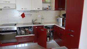 cocina con armarios rojos, fregadero y lavavajillas en Villa Lindos Star in Rodos with Private pool en Kalathos