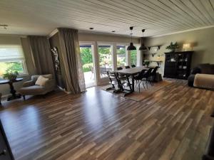 a living room with a wooden floor and a table and chairs at Sentral familievennlig bolig med hage og uteplass in Arendal