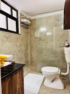 a bathroom with a toilet and a glass shower at Teak Stays in Prayagraj