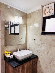 a bathroom with a white sink and a mirror at Teak Stays in Prayagraj