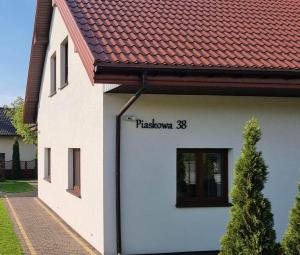 a white building with a sign on the side of it at Dom Mierzeja in Kąty Rybackie