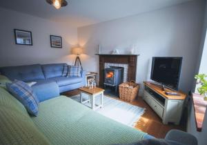 a living room with a blue couch and a fireplace at Min y Don, stone cottage by the edge of the sea, Llangrannog in Llangrannog