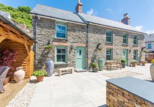 a stone house with a patio in front of it at Min y Don, stone cottage by the edge of the sea, Llangrannog in Llangrannog