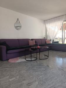 ein Wohnzimmer mit einem lila Sofa und einem Tisch in der Unterkunft Appartement 40m2 Immense Terrasse Angle Piscine Juan les Pins in Antibes